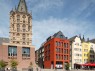Ein signalrotes Haus am Alter Markt in Köln. Links daneben das Rathaus mit dem historischen Rathausturm.