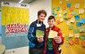 Zwei Jungen halten beschriftete Sprechblasen aus Papier in der Hand.