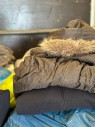 Zwei Winterjacken liegen gefaltet auf Tüten mit Kleidung in einem LKW.