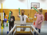 Ein kleinwüchsiger Mann und zwei Kinder werfen Poolnudeln in einen Kasten. 