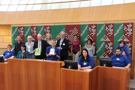 Auf dem Bild sitzen die Umweltassistenten mit ihren Urkunden im Plenumssaal des Landtags NRW und freuen sich.
