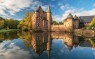 Foto zeigt eine Burg, die sich an der Wasseroberfläche eines See spiegelt.