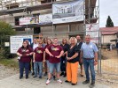 Eine Gruppe von Menschen steht vor einem mit Bauzäunen umzäunten Gebäude.
