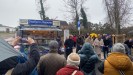Eine Menschenmenge steht vor einem Kiosk. Über dem Kiosk-Dach ist ein Schild mit der Aufschrift: "Zeitungen Karsten", "Frankfurter Allgemeine", "Zeitungen Karsten".