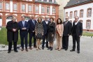 Eine Gruppe lächelnder Menschen in formeller Kleidung steht vor der Abtei Brauweiler.