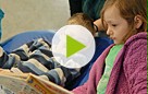 Standbild eines Films, ein Junge und ein Mädchen liegen auf einem Kissen, das Mädchen blättert in einem Buch