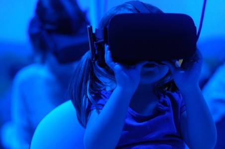 Ein kleines Mädchen benutzt eine VR-Brille. Das Bild ist mit einem blauen Filter belegt.