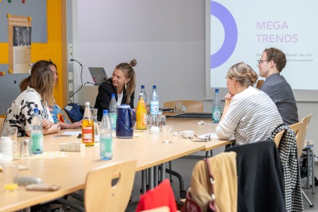 Eine Gruppe von Personen an Tischen sitzend.