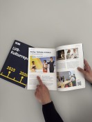 Eine Hand zeigt mit ausgetecktem Finger auf ein aufgeklapptes Buch mit vielen Bildern.