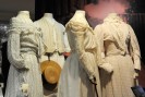 Drei helle Damenkleider und ein Herren-Outfit aus der Zeit von vor 100 Jahren.
