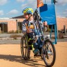 Ein Schuljunge mit einem Rollstuhlfahrrad vor einer Schule, Foto: Nola Bunke