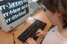 Eine Schülerin mit Sehbehinderung sitzt am Rechner und schreibt. Auf dem Monitor sieht man vergrößerte Buchstaben. Fozo: Ludger Ströter, LVR