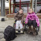 Zwei Grundschulkinder - ein Mädchen und ein Junge - im Rollstuhl vor dem Eingang des Schulgebäudes. Beide lächeln in die Kamera. Foto: Dominik Schmitz, LVR-Zentrum für Medien und Bildung